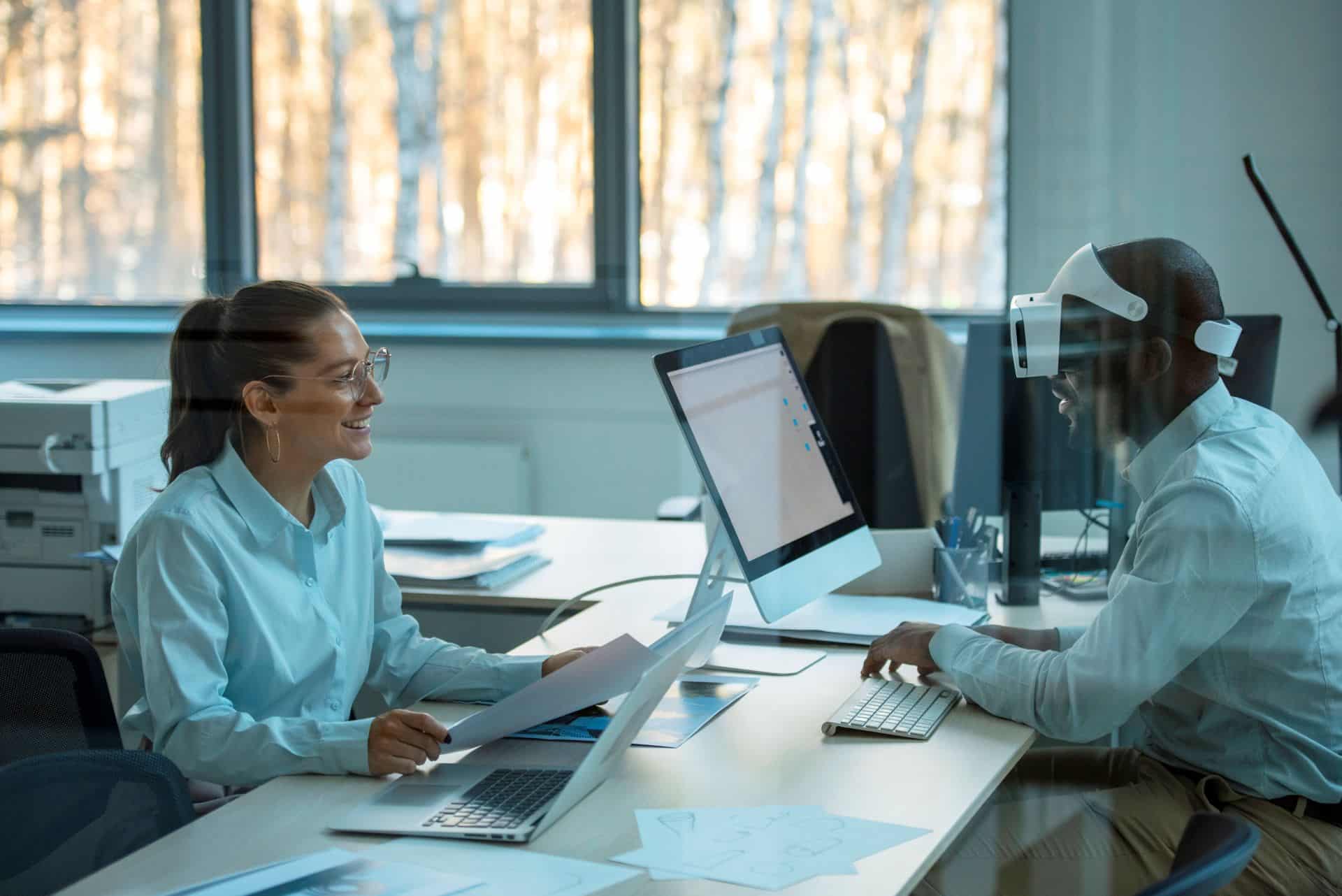 Two colleagues in a modern, bright office working together at a long desk.