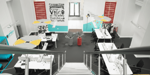 High-angle view from a staircase looking down into a modern, open-plan business hub.