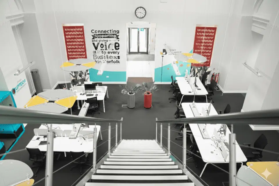 High-angle view from a staircase looking down into a modern, open-plan business hub.