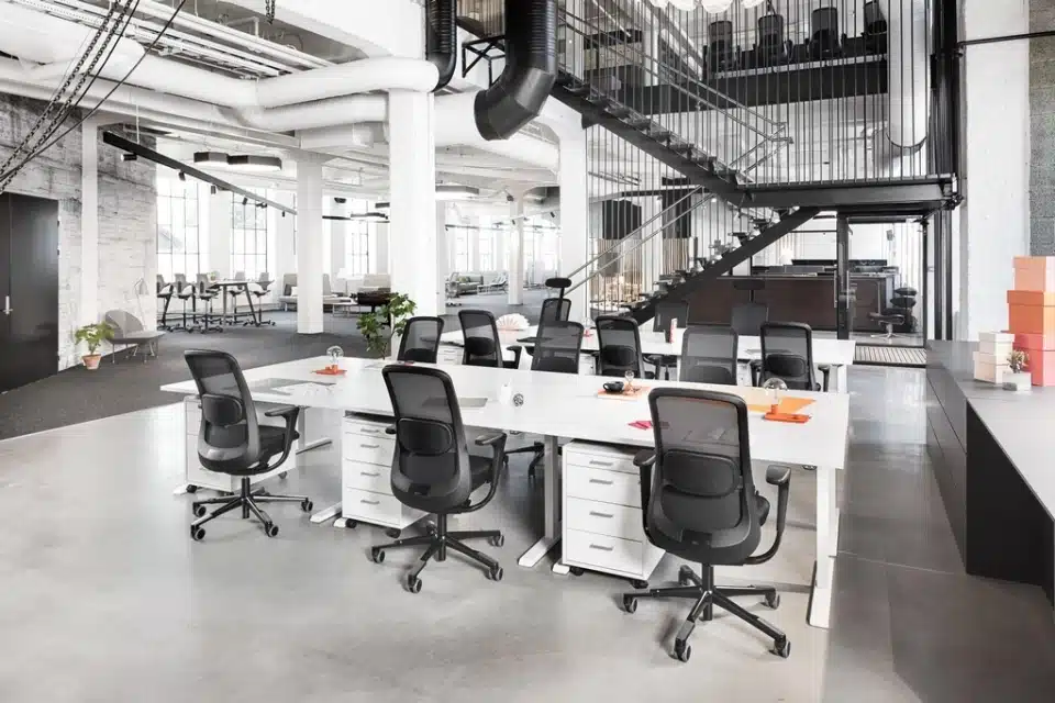 A row of black HÅG SoFi 7500 mesh ergonomic chairs at white sit-stand desks.