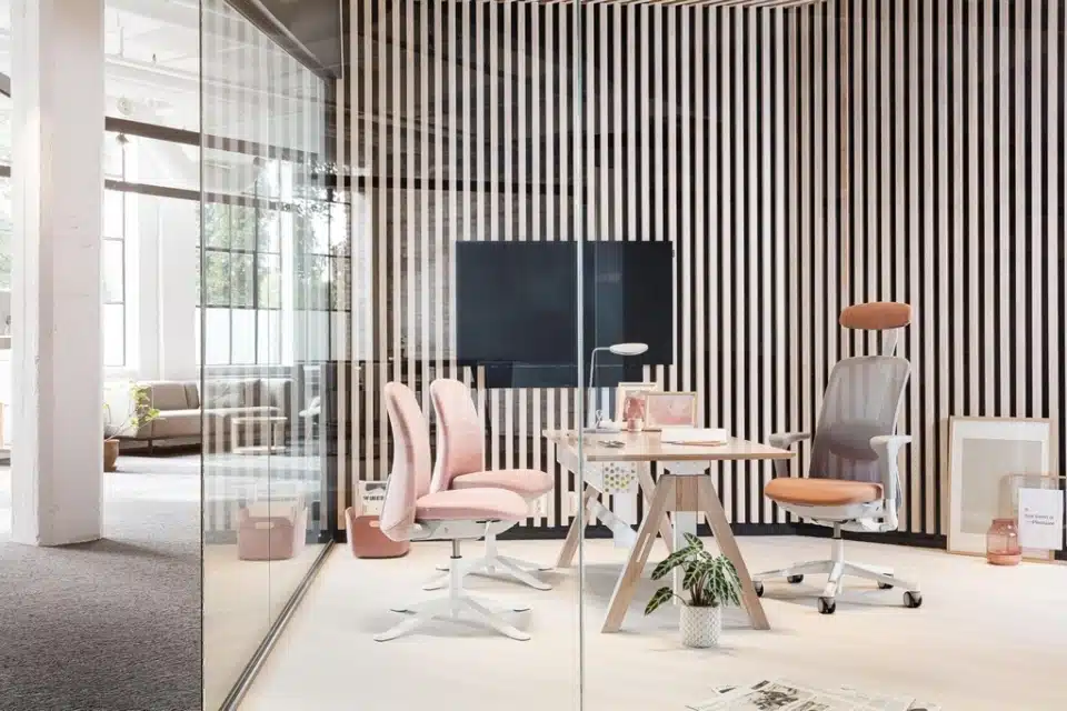 The setting features a HÅG SoFi 7500 mesh chair configured with a headrest and dressed in a soft dusty rose or terracotta textile.