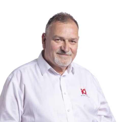 A white male stading in front of a while wall.