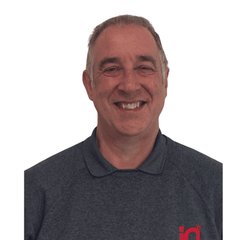 A white male smiling and standing in front of a white wall.