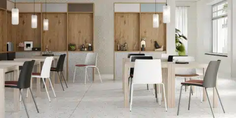 A stylish cafe or breakout area featuring several Seattle chairs in black and white with terracotta seat pads, arranged around light wood tables in a bright, modern interior.
