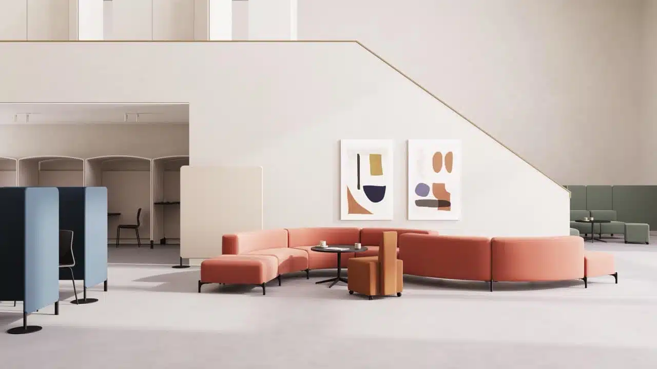 A modern, open-plan office lounge featuring a modular, curved terracotta-colored sofa arranged in a semi-circle around a black coffee table. The space is minimalist, with high ceilings, neutral white walls, abstract art, and blue acoustic privacy screens.
