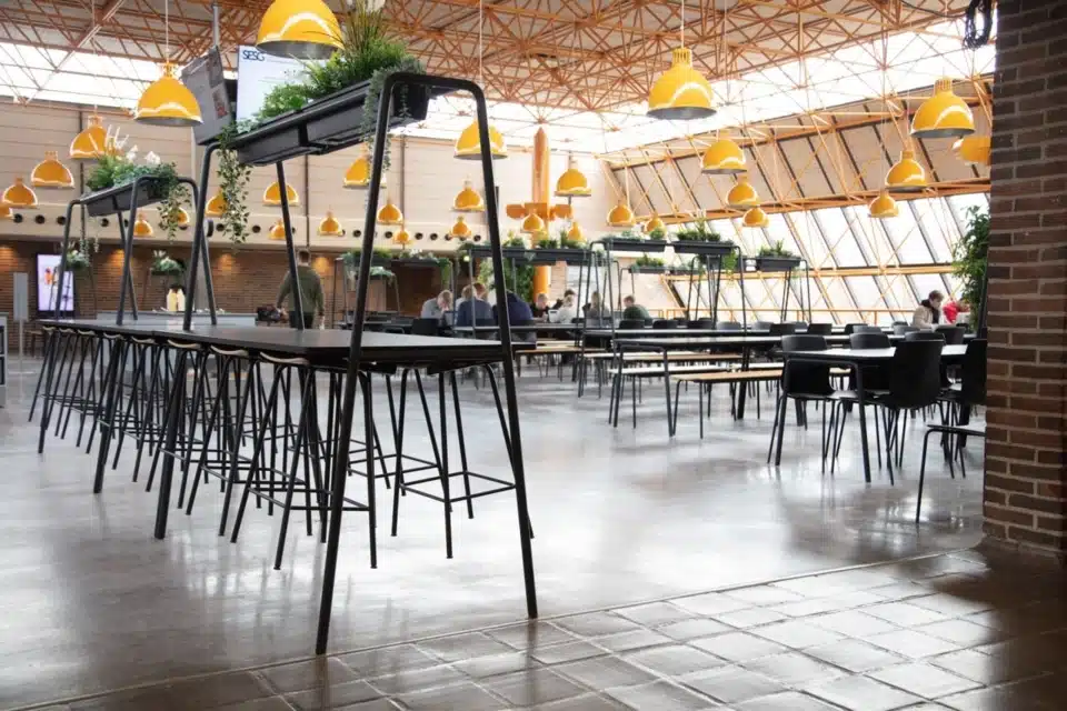 FourReal® 74 high tables with A-frame Room In Room planters in a large canteen