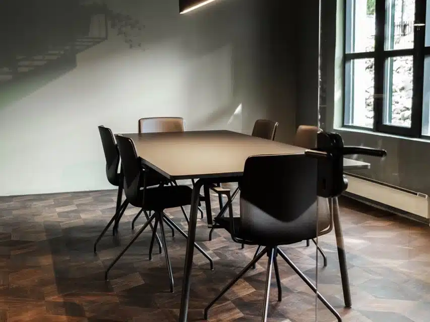 FourReal® 74 meeting table with black swivel chairs in a modern professional boardroom.