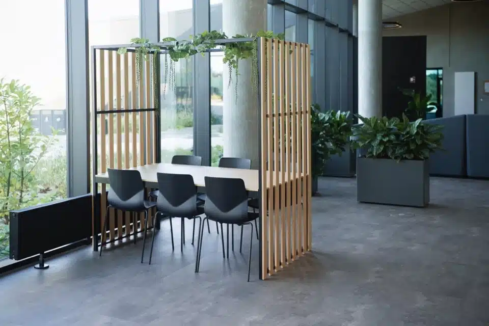 Black FourSure 44 chairs in a biophilic wooden meeting pod within a modern office.