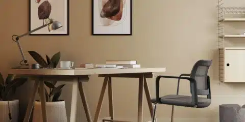 Modern office design featuring a light wood trestle desk and a black mesh cantilever task chair in a warm, contemporary iQ Workspace setting.