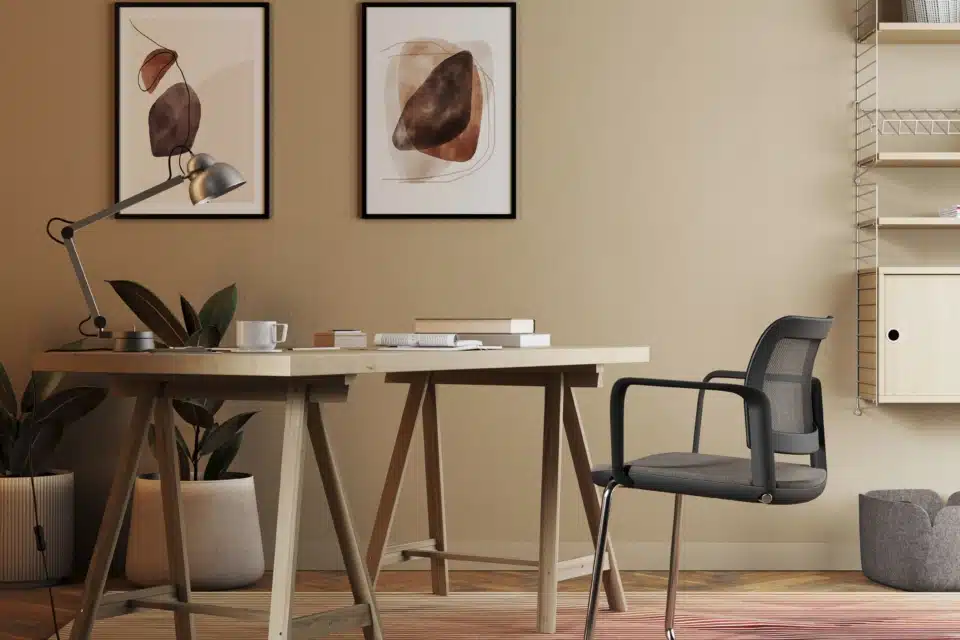 Modern office design featuring a light wood trestle desk and a black mesh cantilever task chair in a warm, contemporary iQ Workspace setting.