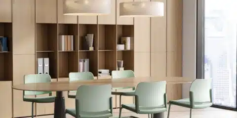 Modern iQ Workspace meeting room design featuring an oval wooden table and six green cantilever chairs against a floor-to-ceiling light oak storage wall.