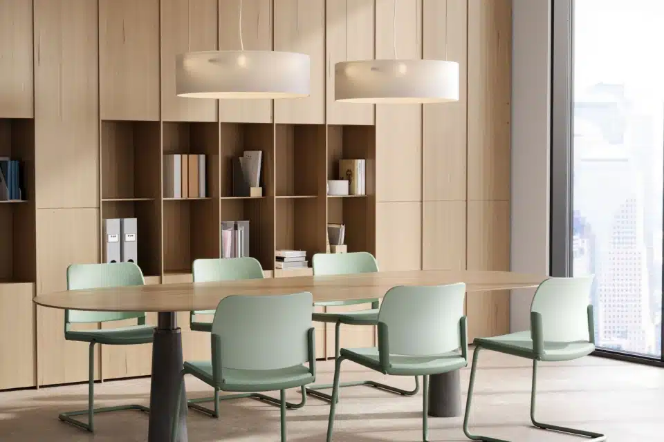 Modern iQ Workspace meeting room design featuring an oval wooden table and six green cantilever chairs against a floor-to-ceiling light oak storage wall.