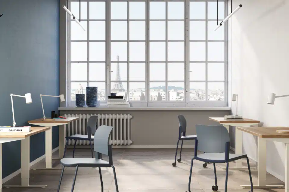 Commercial office design featuring individual sit-stand desks and mobile blue task chairs in a modern iQ Workspace setting with a view of the Eiffel Tower.