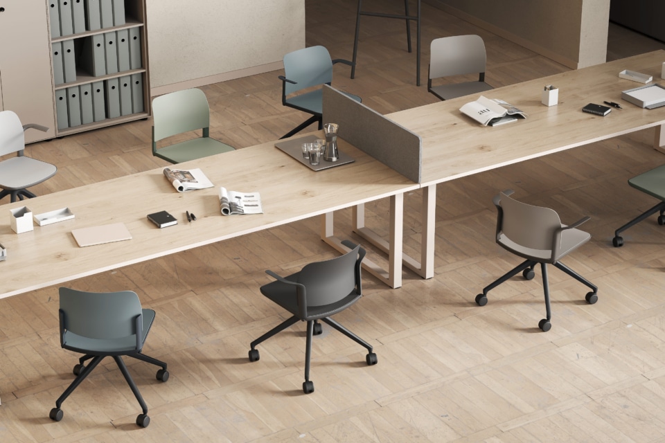 Modern commercial office design featuring a long wooden co-working desk with muted colour task chairs on a herringbone wooden floor.