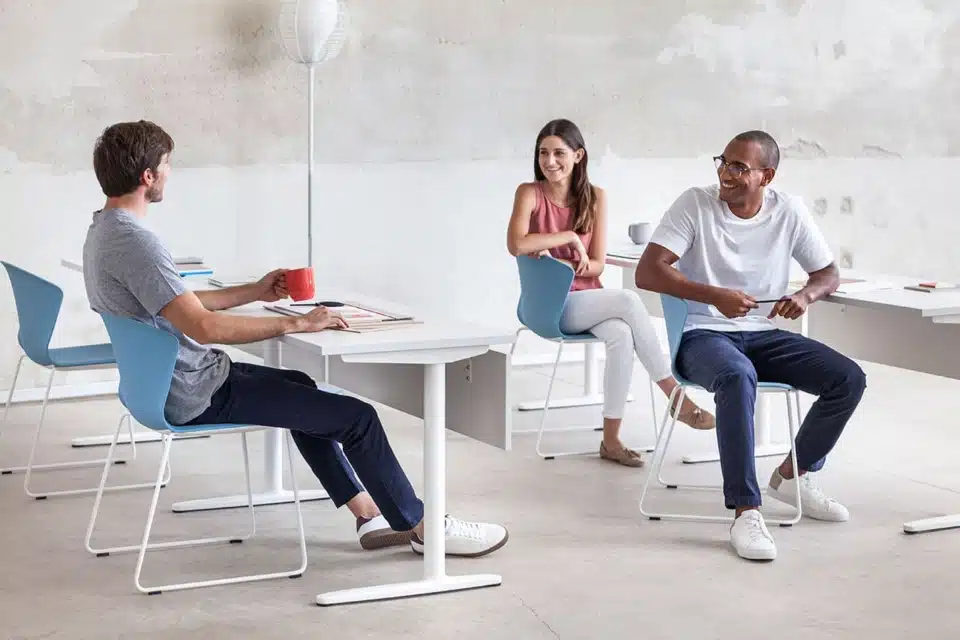 Professional training room environment featuring three team members collaborating at individual white Talent desks with light blue chairs.