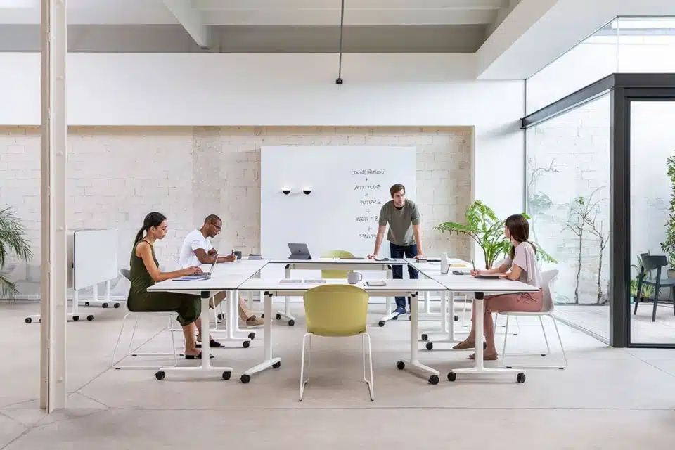 Professional collaborative training space featuring flexible white Talent tables arranged in a U-shape, paired with ergonomic seating for a team meeting.