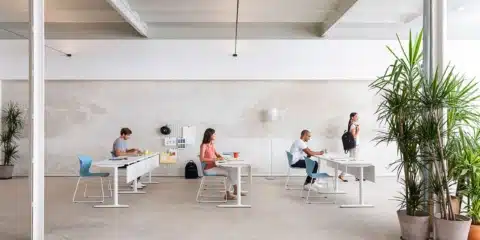 Modern open-plan training room featuring individual white desks and light blue seating in a bright commercial office design.