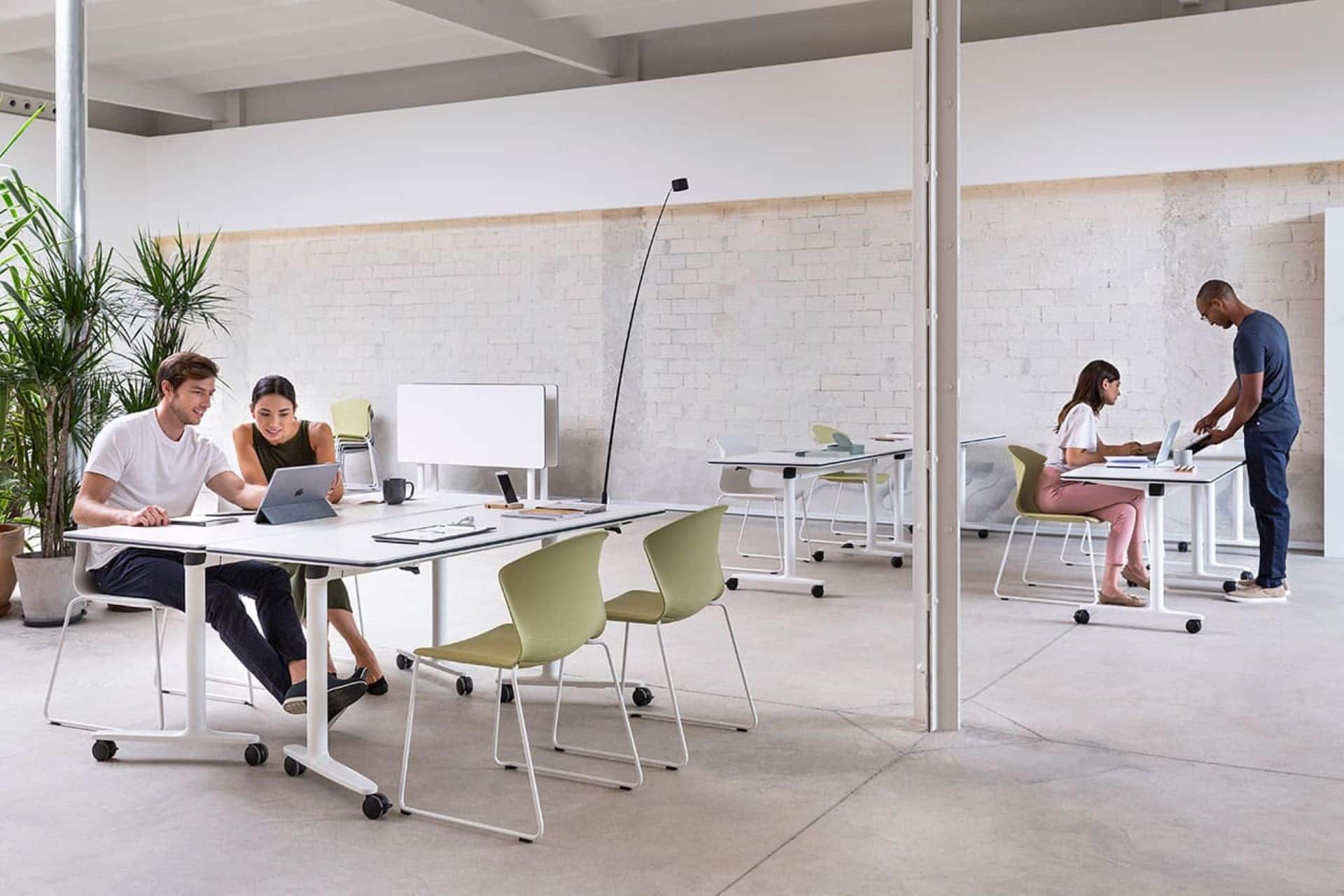 Modern open-plan office design featuring flexible white mobile desks and light green chairs in a collaborative workspace.