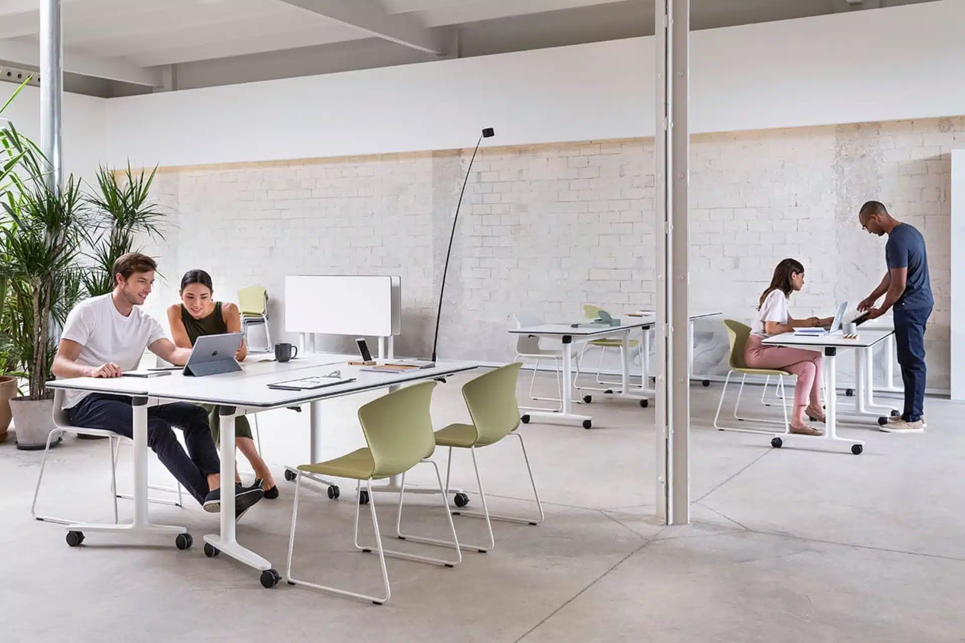Modern open-plan office design featuring flexible white mobile desks and light green chairs in a collaborative workspace.